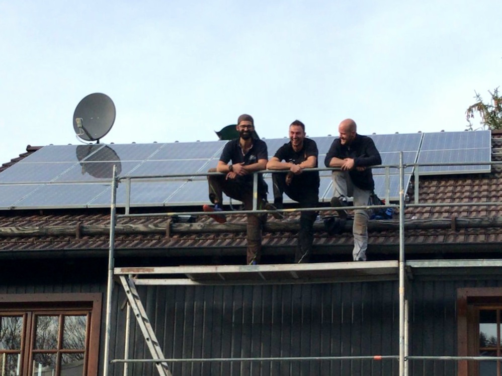 Montageteam auf Gerüst vor fertig installierter Solaranlage
